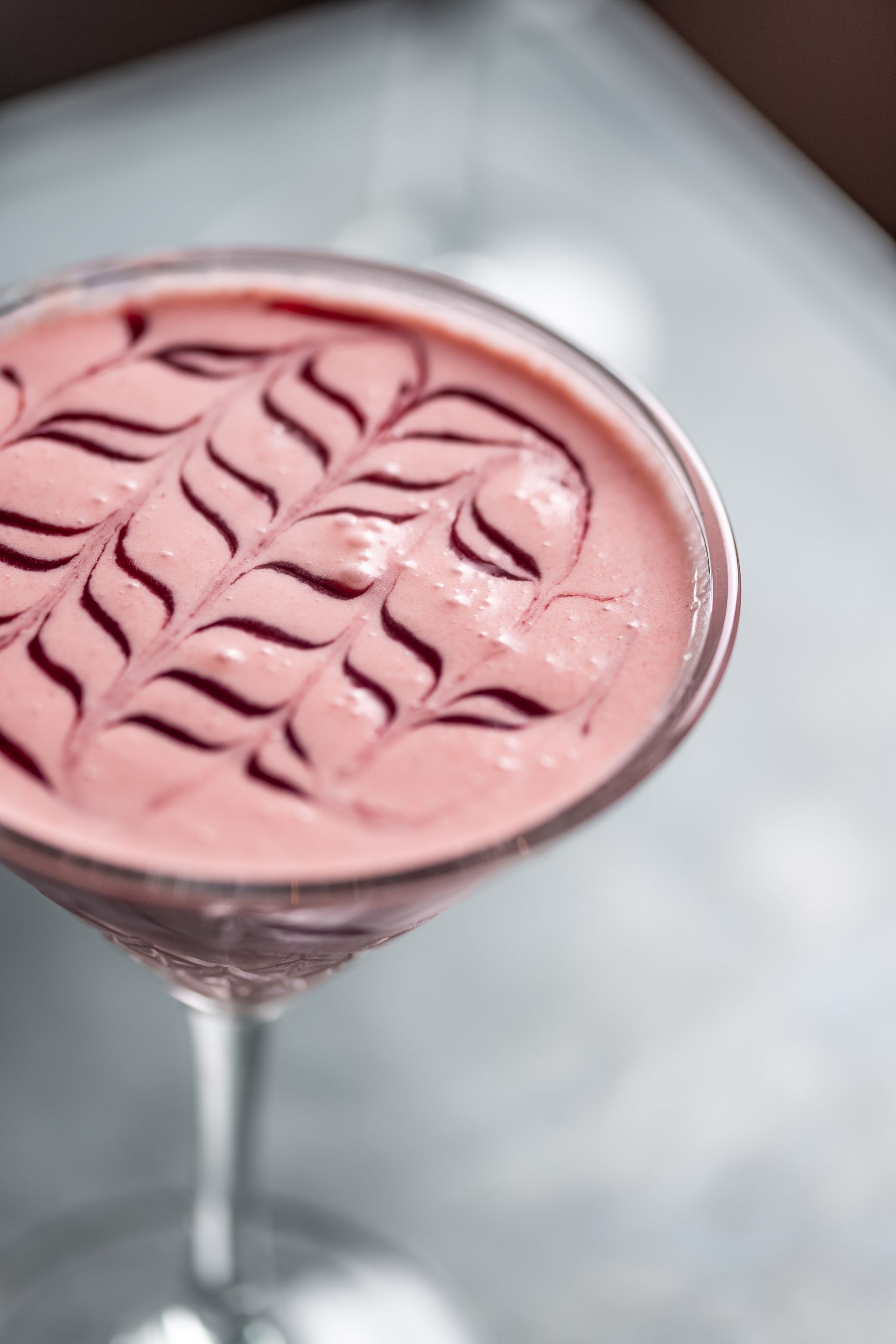 A close up of a pink drink in a martini glass