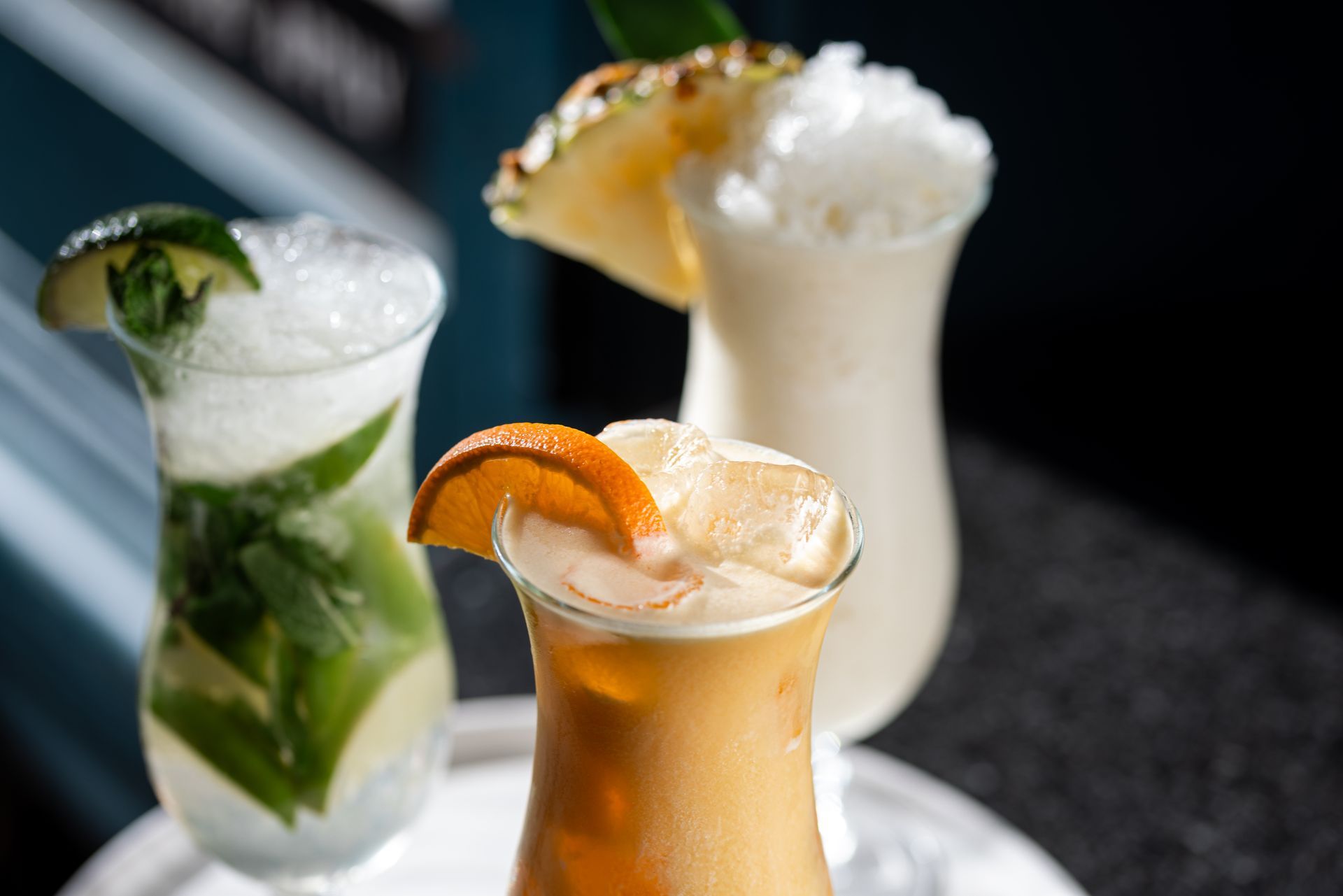 Three different types of cocktails are sitting on a white plate on a table.