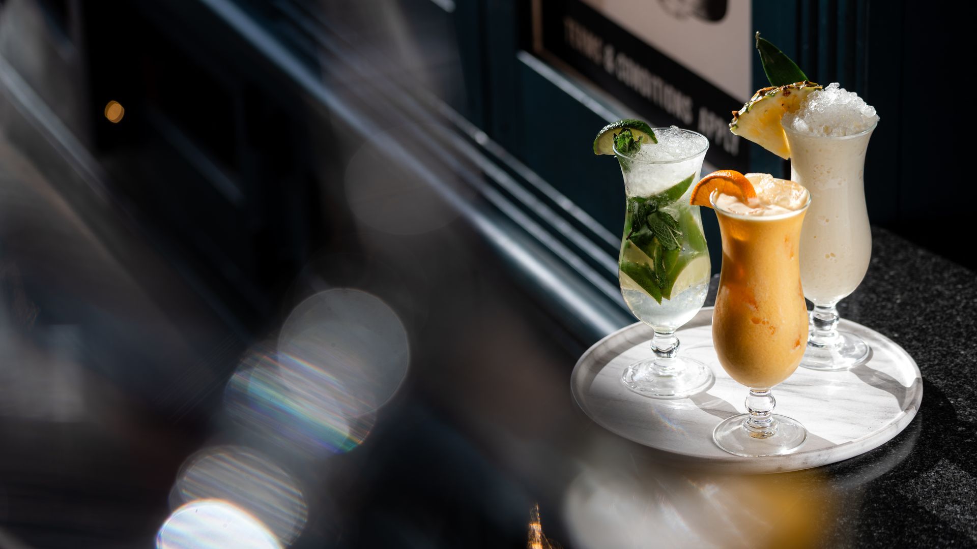 Three cocktails are sitting on a tray on a table.