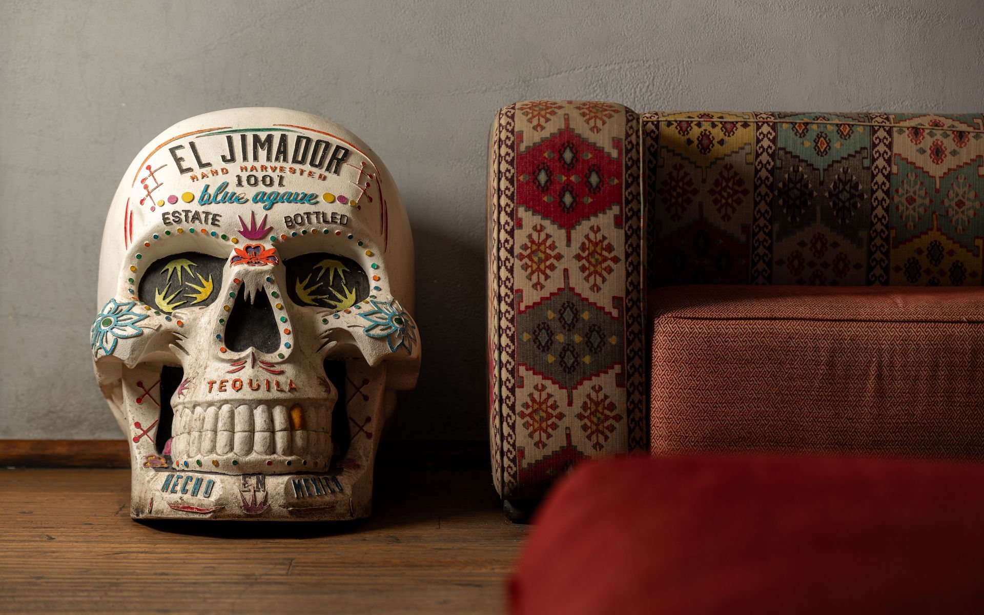 A sugar skull is sitting next to a couch in a living room.