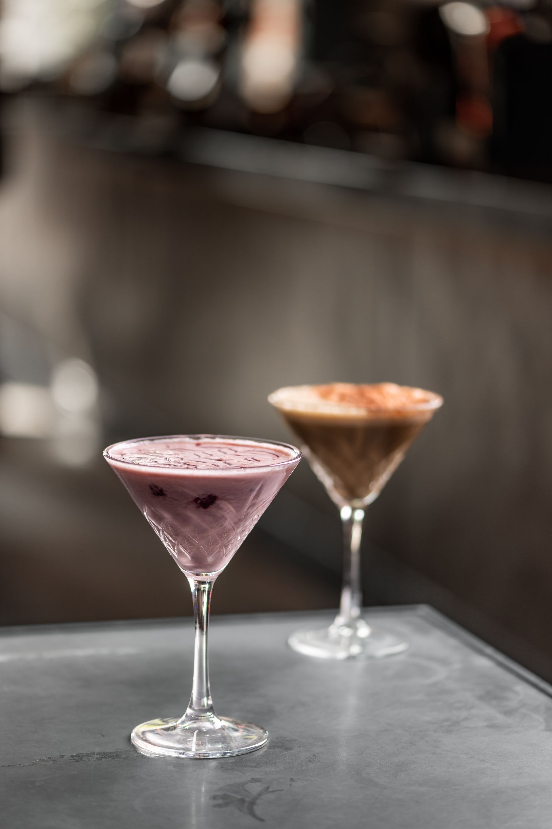 Two martini glasses filled with different types of drinks are sitting on a table.