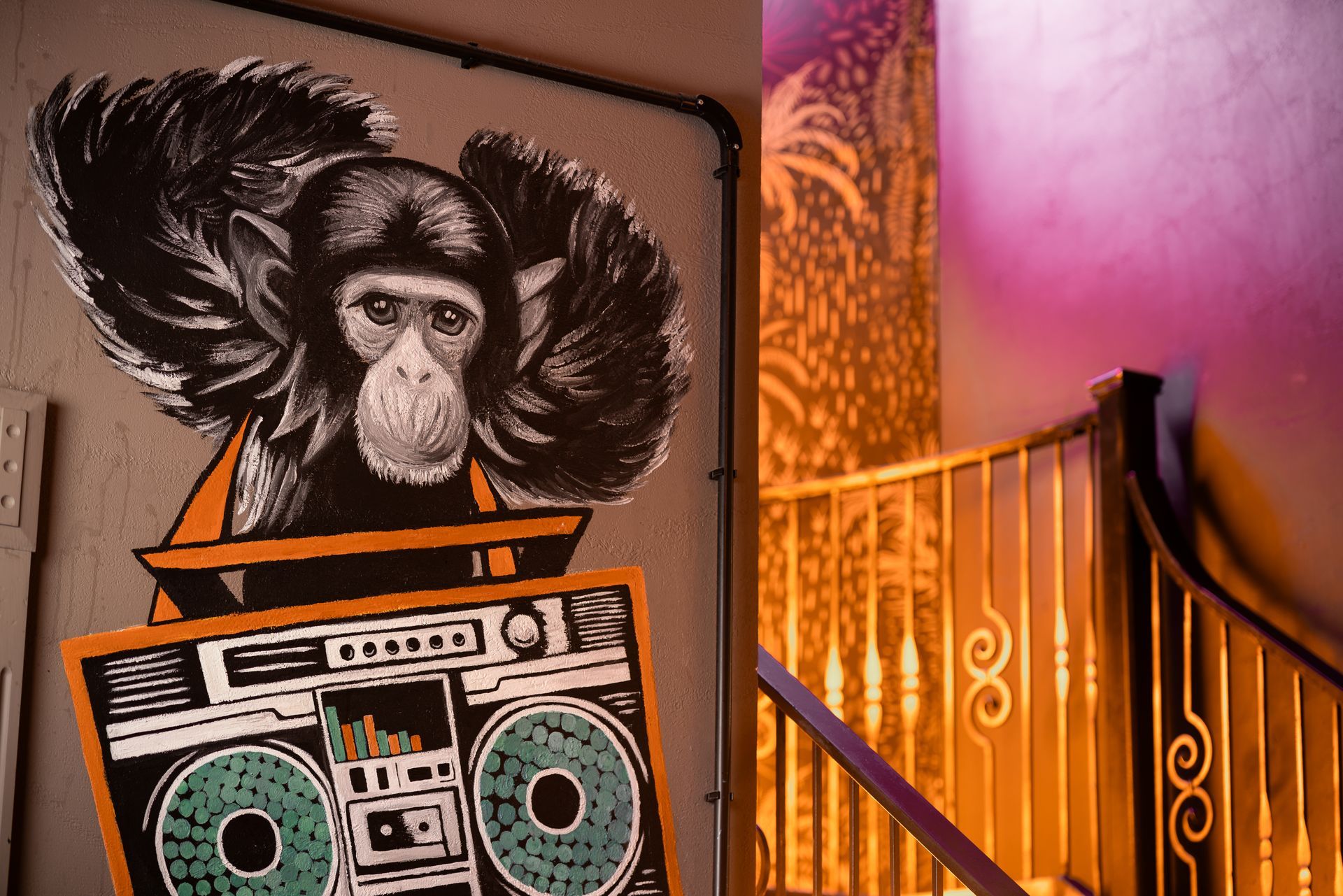 A monkey is sitting on top of a boombox on a wall.