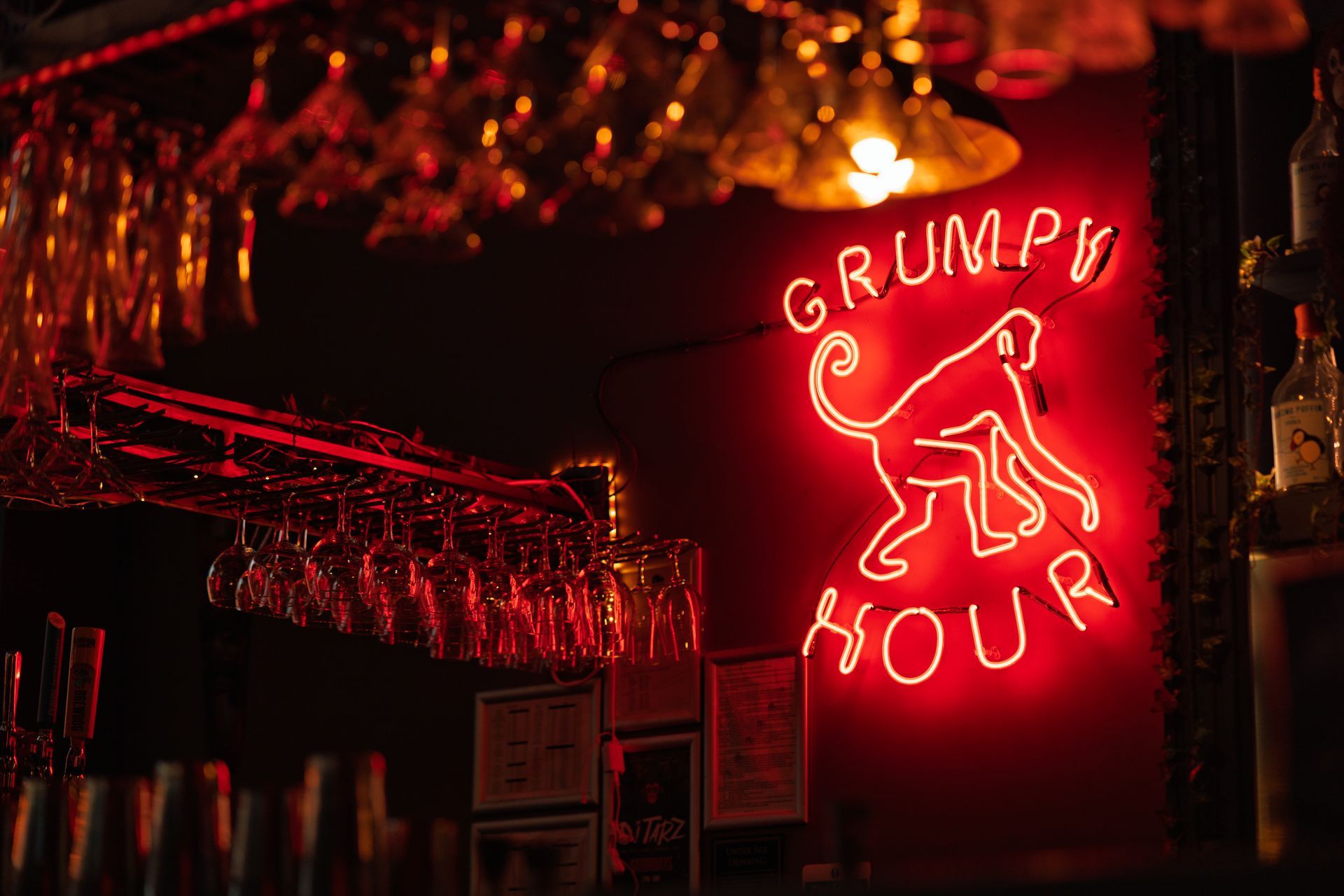 A neon sign that says grumpy hour with a monkey on it