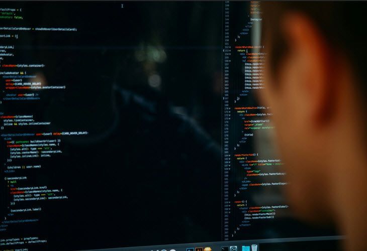 A man is looking at a computer screen with a lot of code on it.