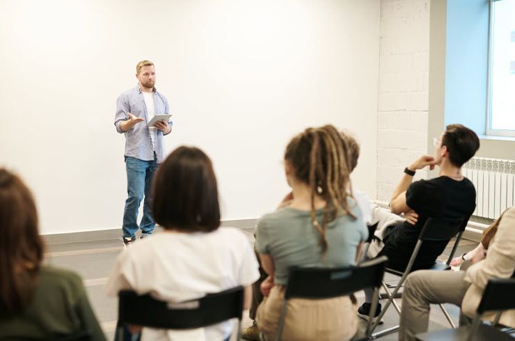 A man is giving a presentation to a group of people sitting in chairs.