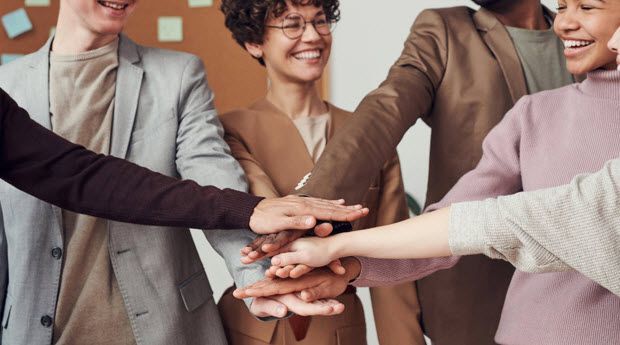 A group of people are putting their hands together.