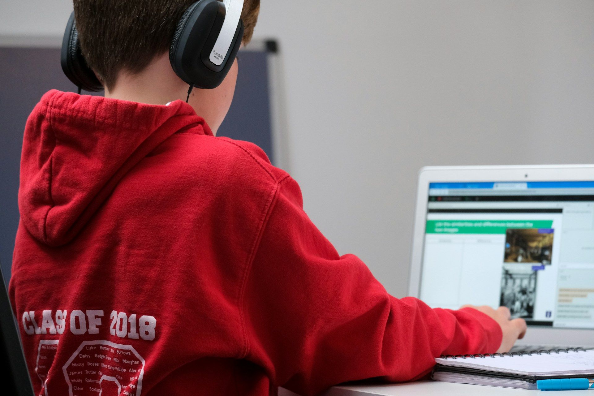 A boy wearing headphones is using a laptop computer.