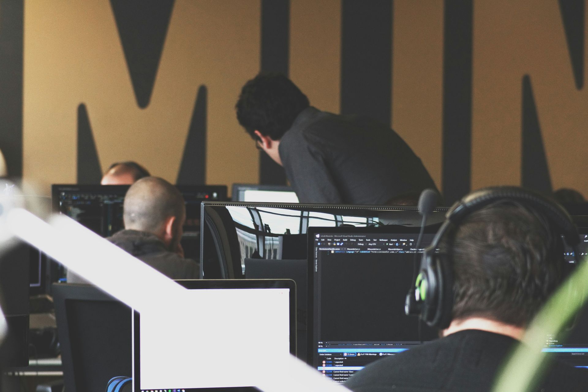 A man wearing headphones sits in front of a computer monitor