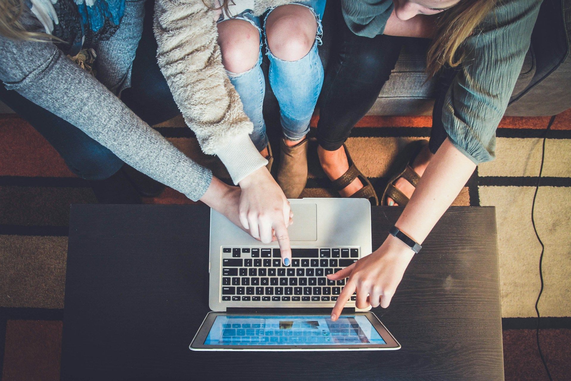 Three women are sitting on a couch looking at a laptop computer.