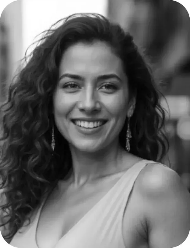 A woman with curly hair is smiling in a black and white photo