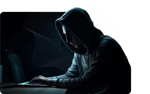 A man in a hoodie is typing on a laptop computer.