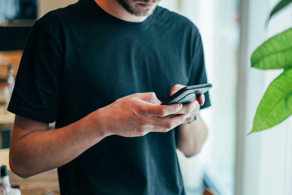 A man in a black shirt is using a cell phone.