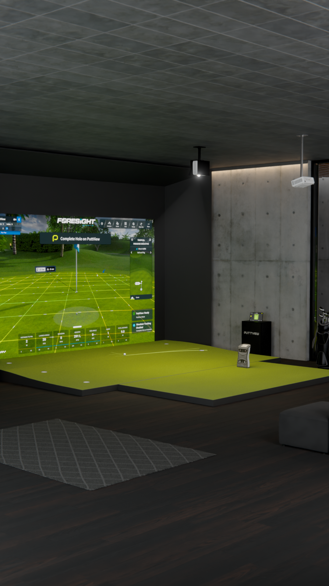 Indoor golf simulator with green turf, screen displaying a golf course, and a concrete wall.