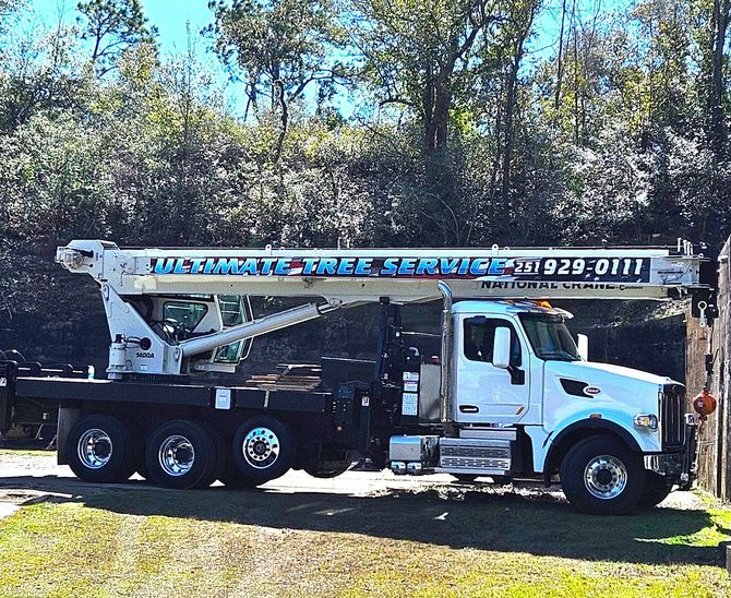 A white truck with a crane on top of it is parked in a grassy field.