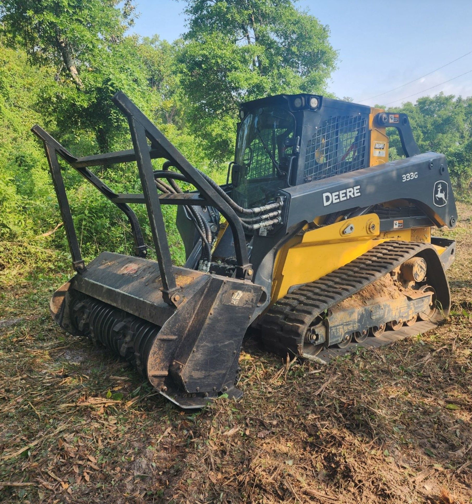 A yellow and black Deere tractor is sitting in the middle of a field.