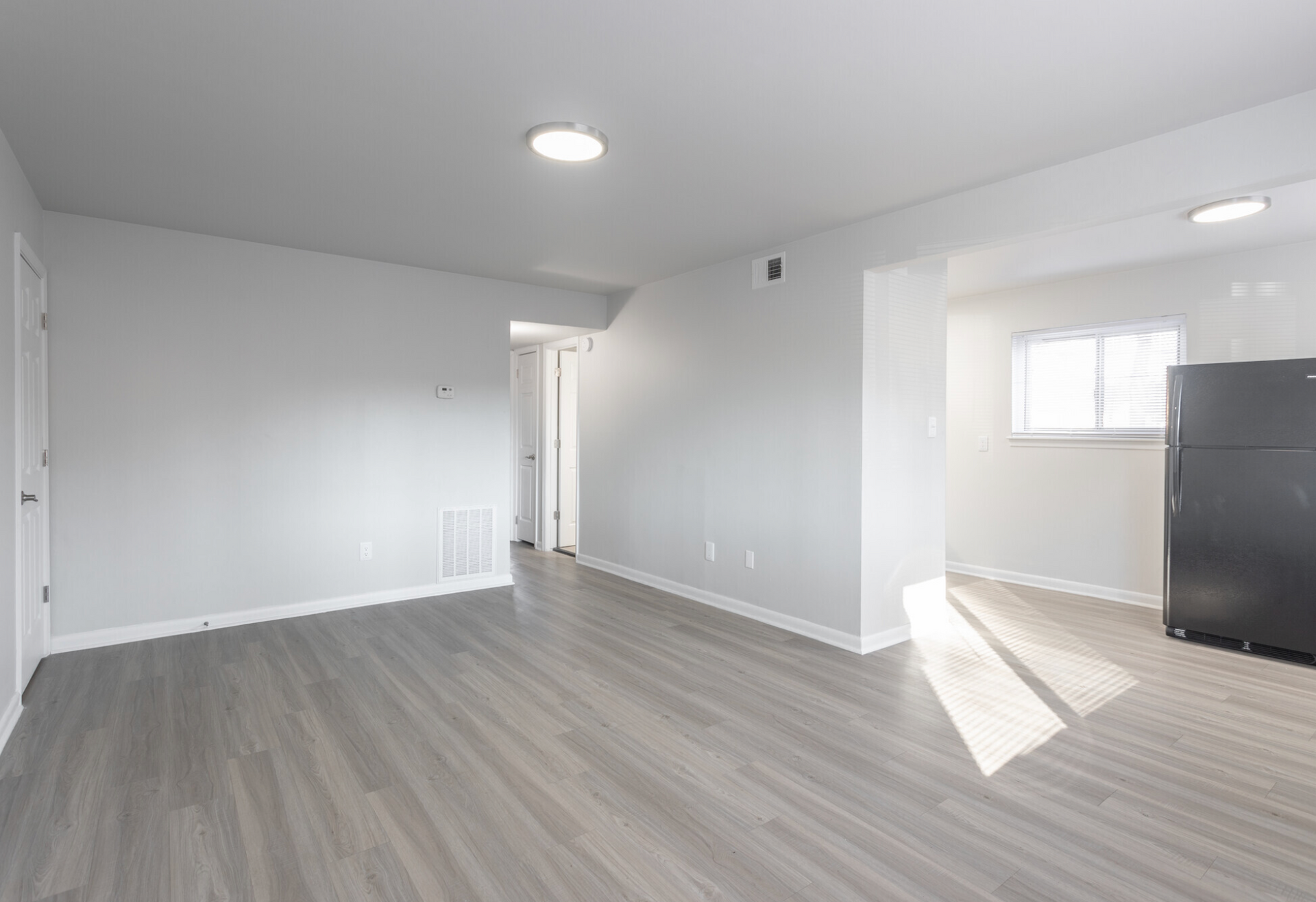An empty living room with hardwood floors and white walls.