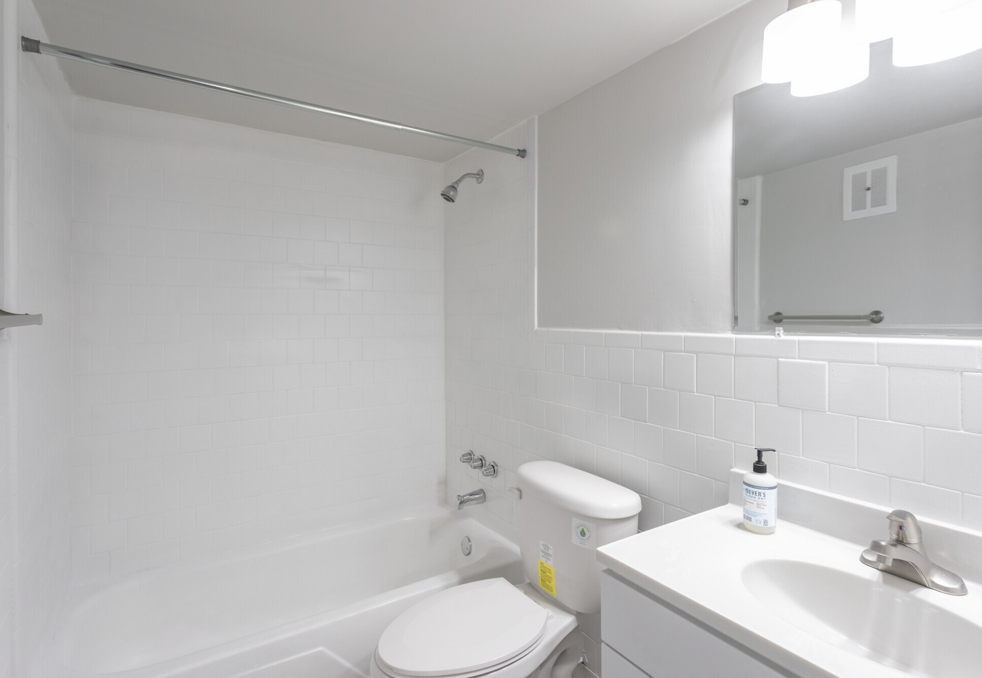 A bathroom with a toilet , sink , shower and mirror.