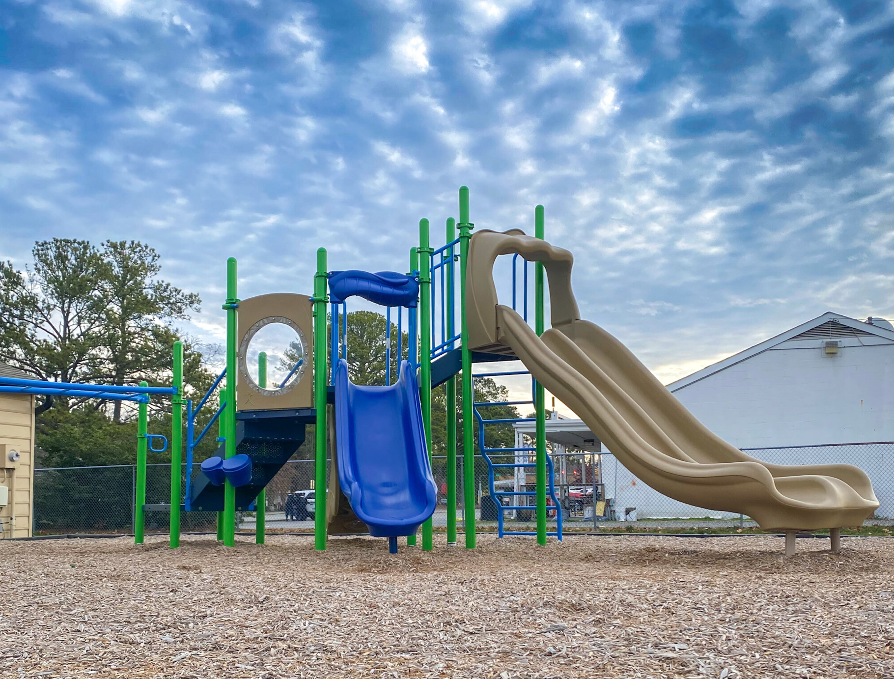 A playground with a blue slide and a brown slide
