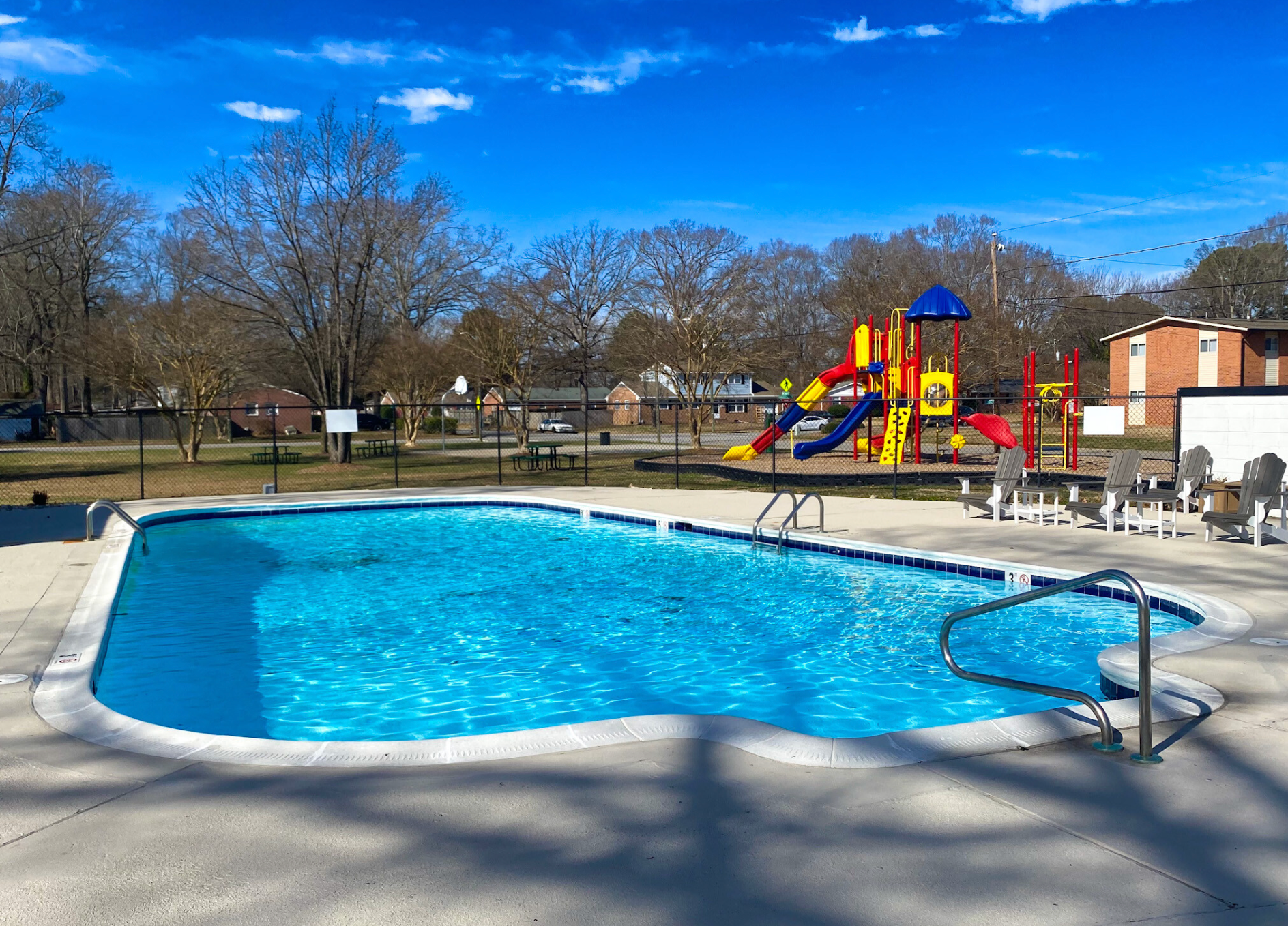 A large swimming pool with a playground in the background.