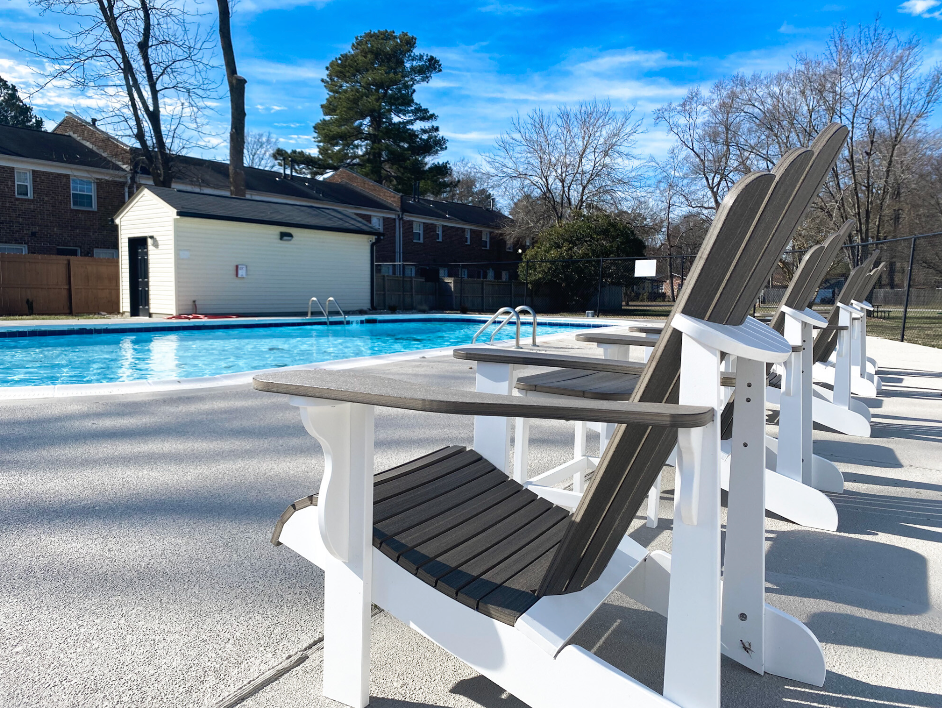 A row of chairs are lined up in front of a swimming pool