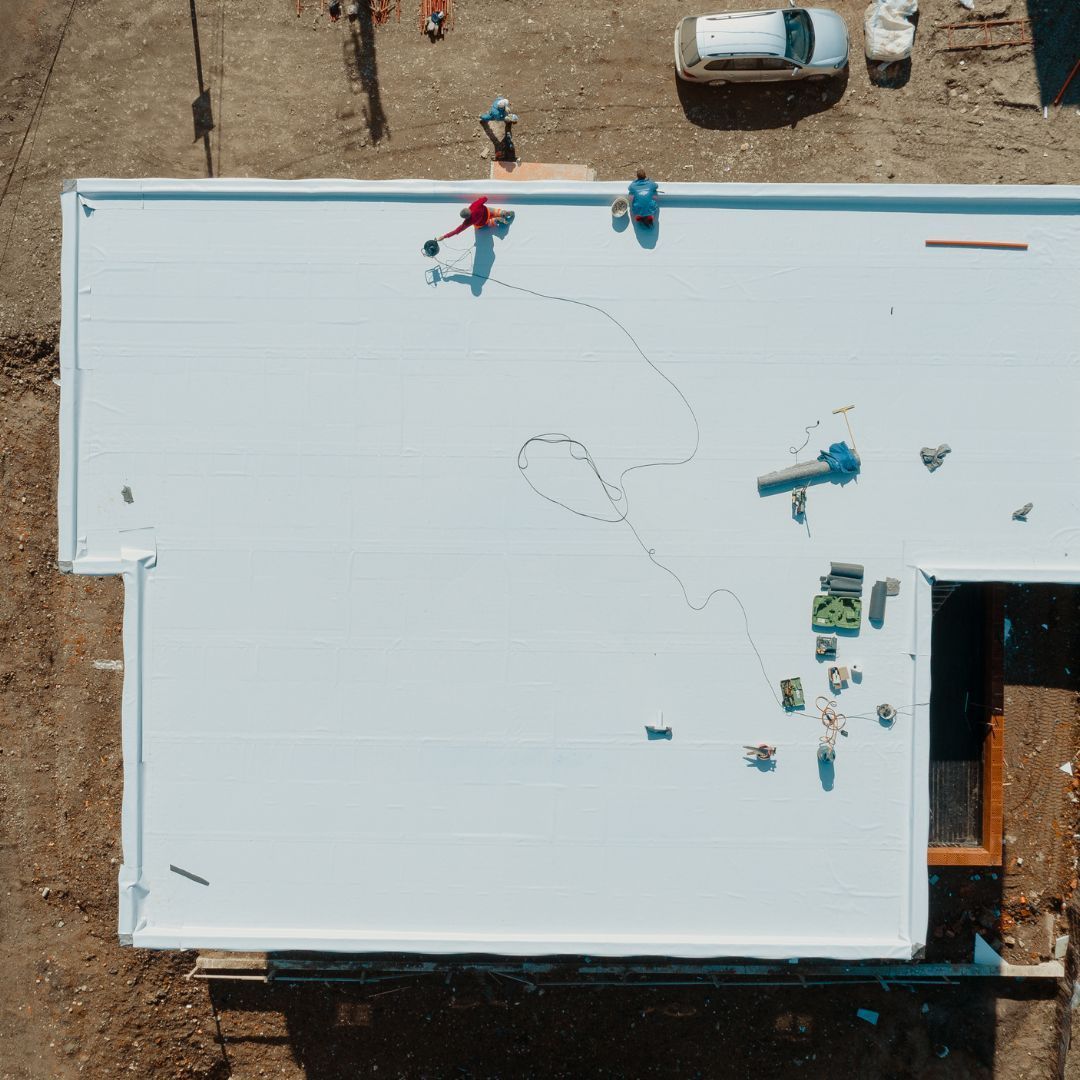 An aerial view of a building under construction with a white roof.