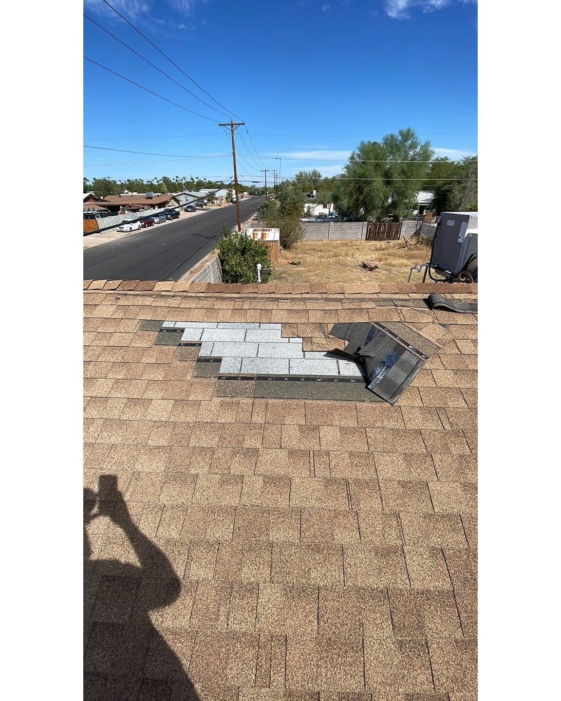 A roof with a hole in it and a shadow of a person taking a picture of it.