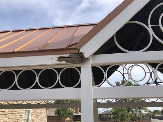 A gazebo with a copper roof and a white frame