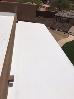 A white roof with a pergola in the background is sitting on top of a building.