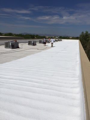 A group of people are standing on top of a white roof.