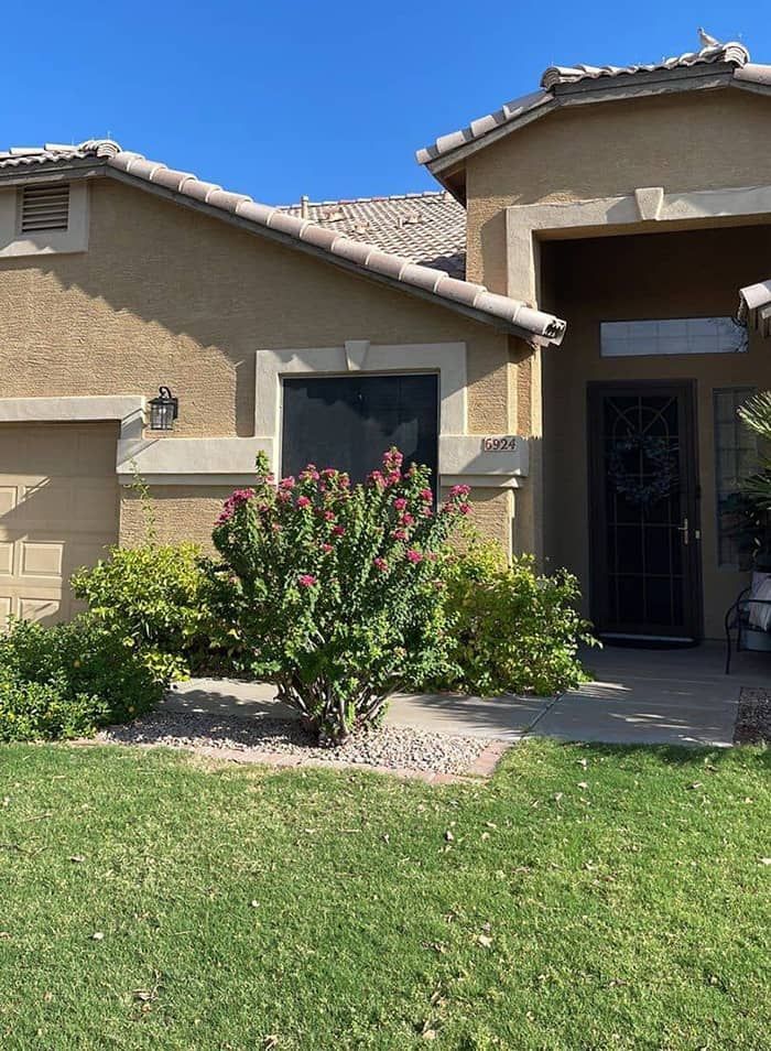 The front of a house with a bush in front of it.