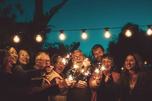 Group of people holding fireworks while smiling and laughing