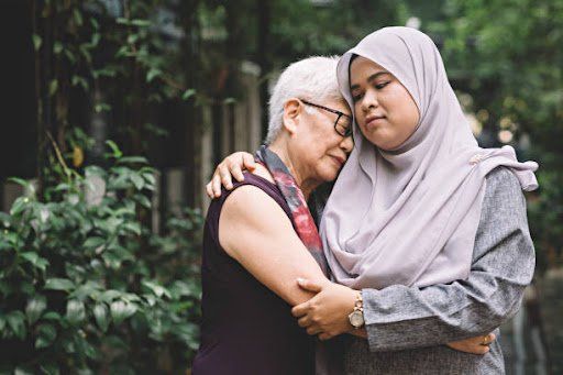 Young woman comforting an older woman with a hug.