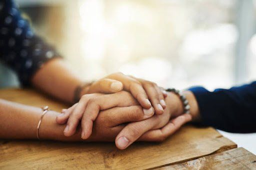 Person offering support to loved one by holding their hand