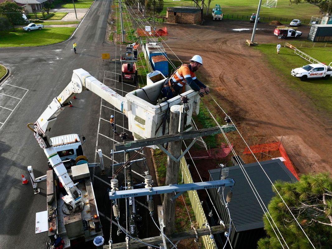 Utility workers in a cherry picker repair power lines on a residential street.