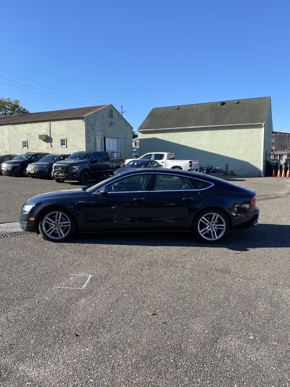 A black car is parked in a parking lot in front of a building. | InTown Auto Care