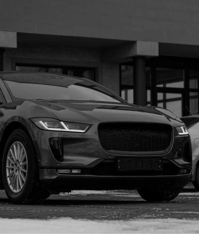 A black and white photo of a jaguar i pace parked in front of a building. | InTown Auto Care