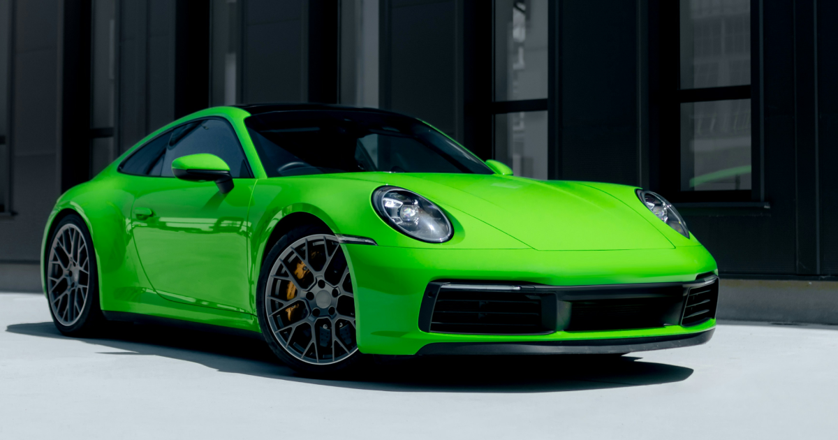 A green porsche 911 is parked in front of a building. | InTown Auto Care