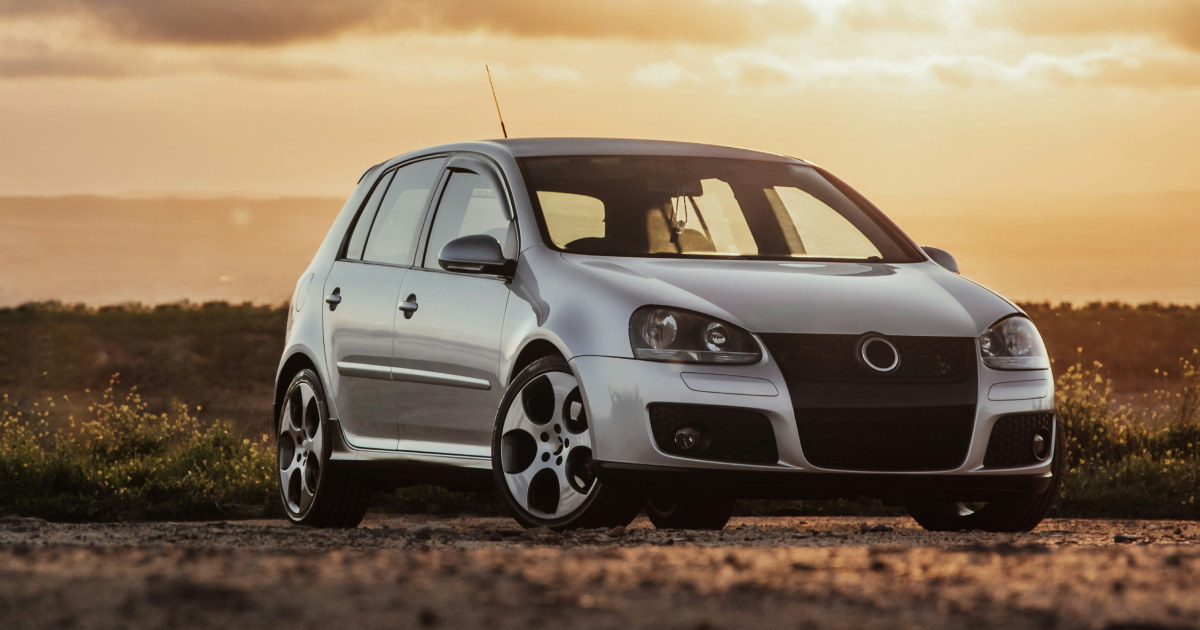 A silver volkswagen golf is parked on a dirt road at sunset. | InTown Auto Care