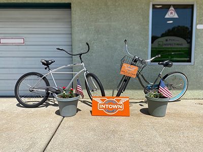 Two bicycles are parked on the sidewalk in front of a building. | InTown Auto Care