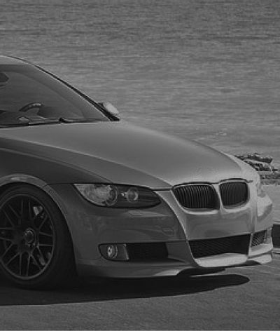 A black and white photo of a bmw 3 series parked next to a body of water. | InTown Auto Care