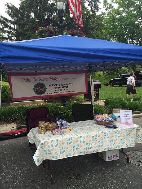 A table under a blue tent with a sign that says bake the pink pink | InTown Auto Care