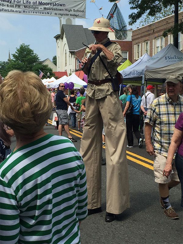 A man on stilts is playing a guitar at a festival | InTown Auto Care