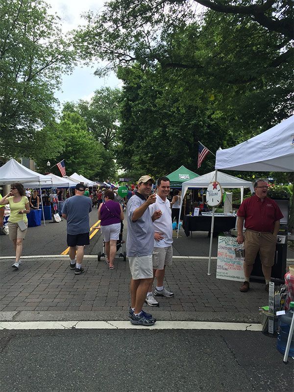 A group of people are standing in front of tents at a market. | InTown Auto Care