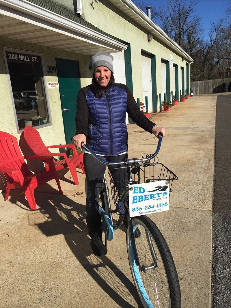 A woman is riding a bike in front of a building. | InTown Auto Care