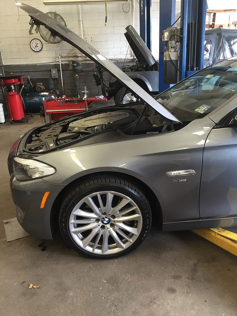 A Car With its Hood up is on a Lift in a Garage - InTown Auto Care