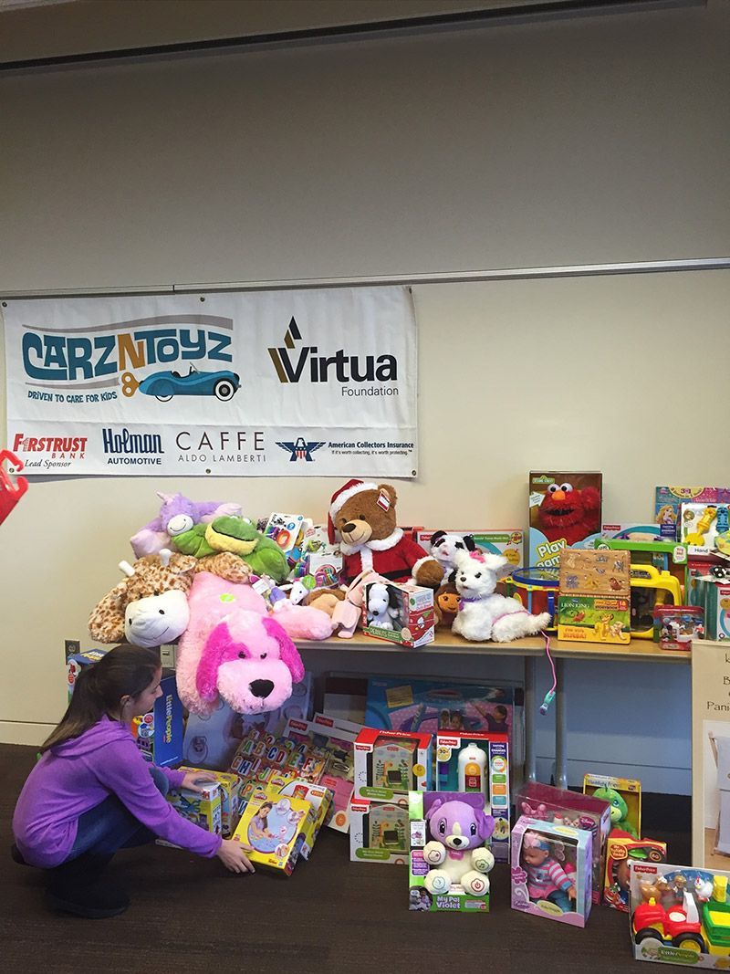 A girl is kneeling in front of a table full of toys. | InTown Auto Care