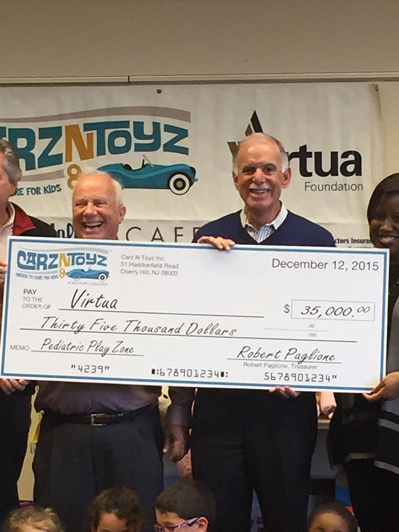 A group of people holding a large check in front of a sign that says carztoyz | InTown Auto Care