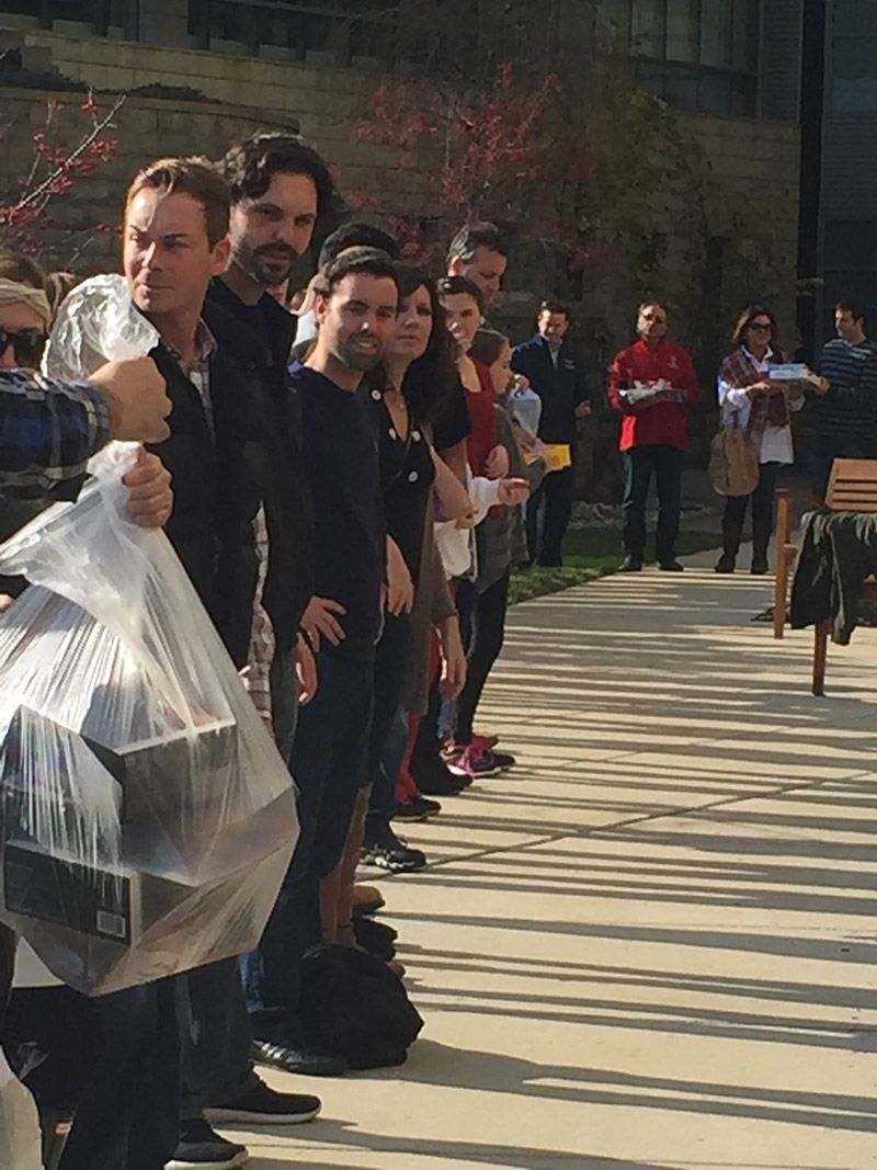 A group of people are standing in a line holding plastic bags. | InTown Auto Care