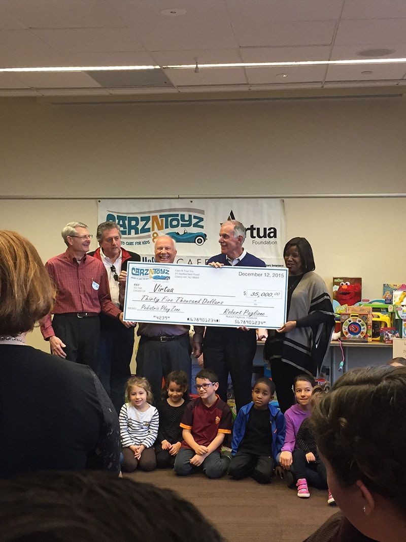 A group of people are holding a large check in a room. | InTown Auto Care