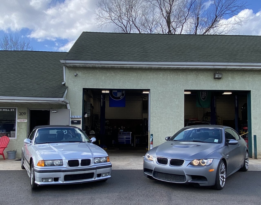 Two silver cars are parked in front of a garage. | InTown Auto Care